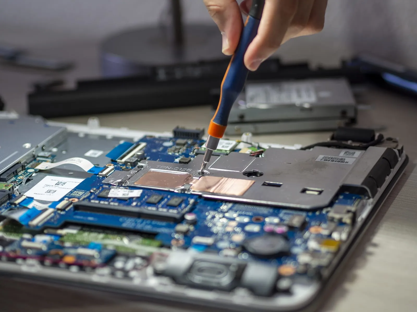 An engineer repairing a laptop motherboard with a precision screwdriver