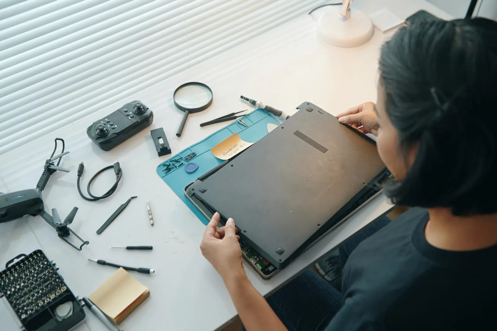 An engineer working on a laptop at a tidy repair bench