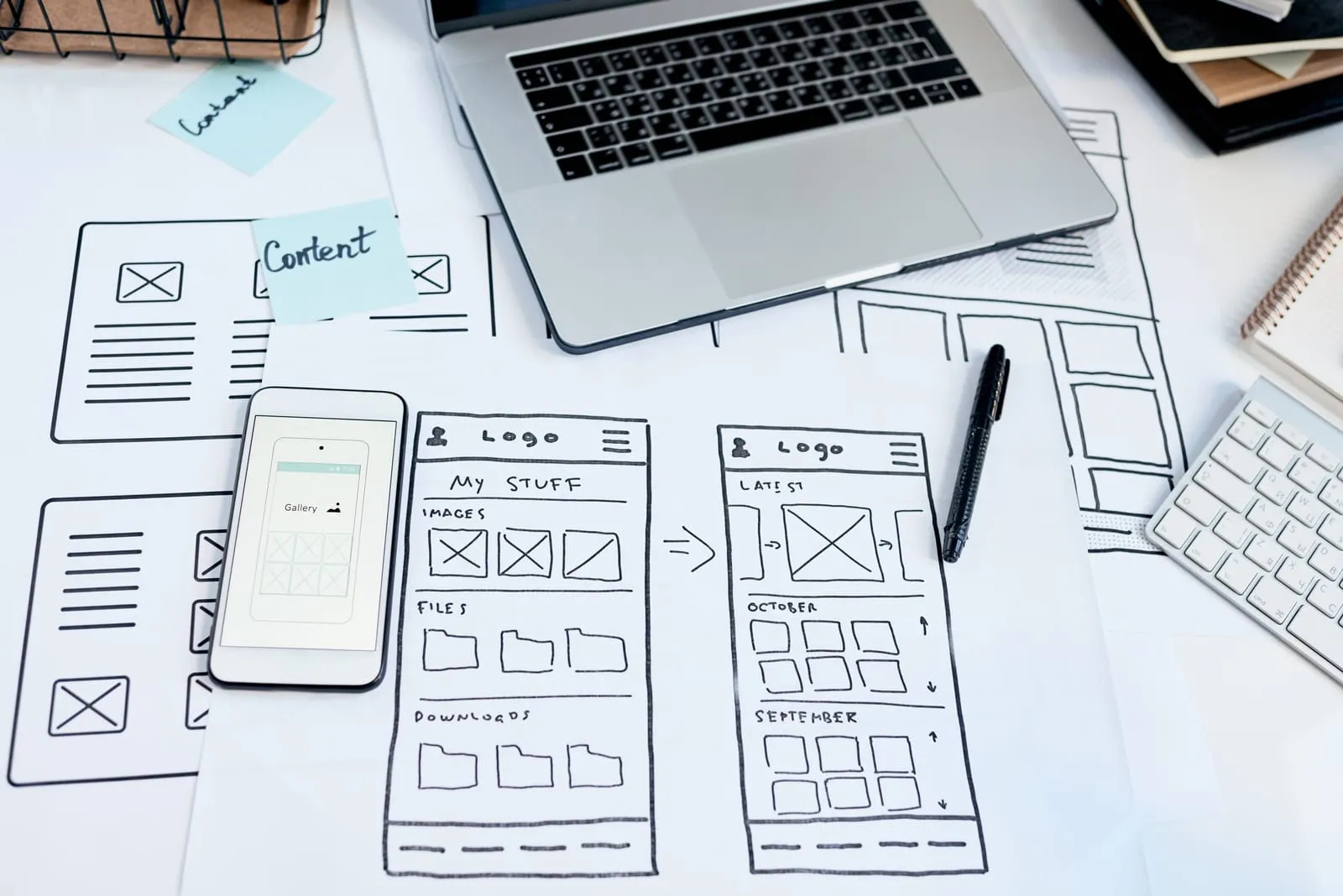 Website and mobile app wireframe sketches beside a laptop and phone
